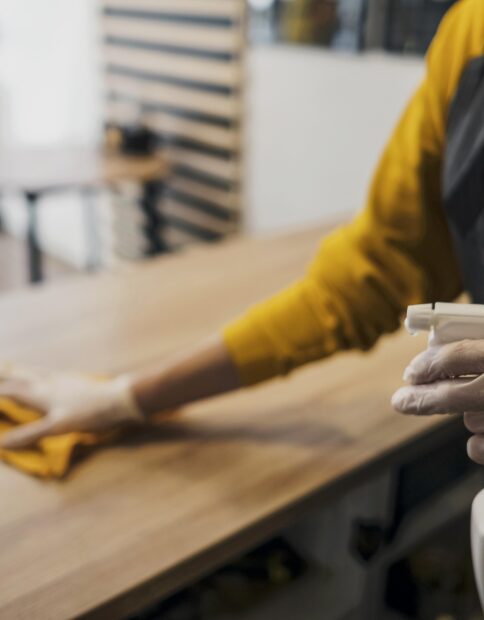 side-view-female-barista-cleaning-table-while-wearing-latex-gloves